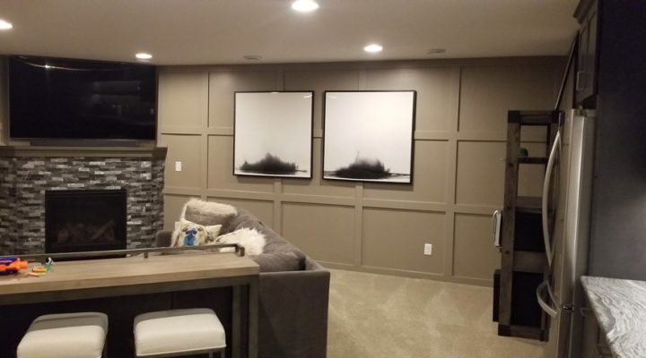 A living room with flat screen, a fireplace, a carpeted floor, and two art displays