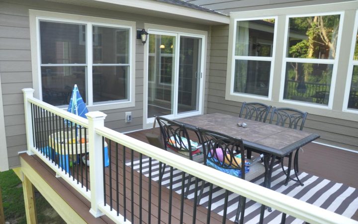 A deck constructed as a veranda of a house with chairs and table for outdoor conversations and gatherings.