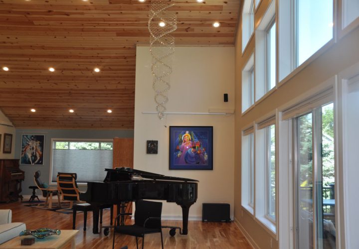 Artistic hanging lights from a wood plank ceiling of a living room with a piano, and a wall art display