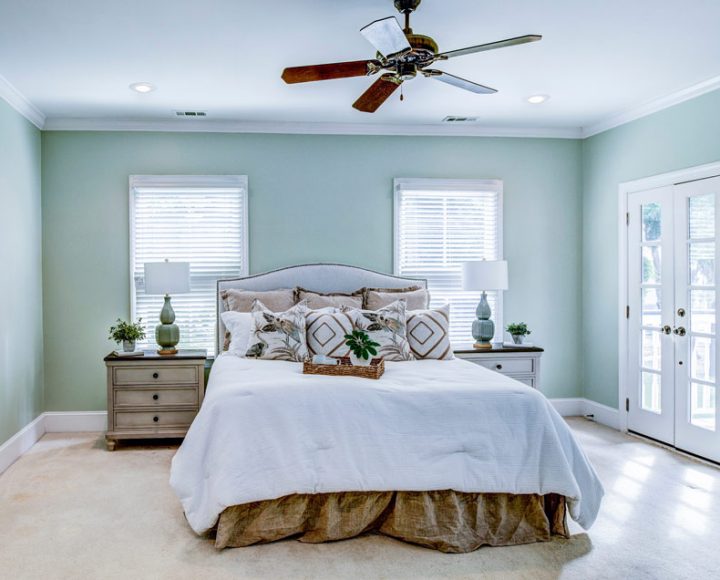 Master Bedroom with walls painted in cool green, and side tables with lamps, and a ceiling fan